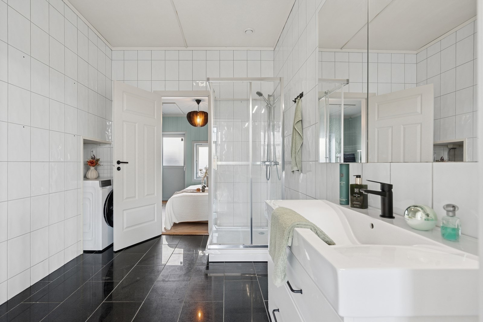 Badet har adkomst fra kjøkken og soverom. Rommet er innredet med innredning med nedfelt servant, speilskap, dusjkabinett og opplegg for vaskemaskin. Galleribilde