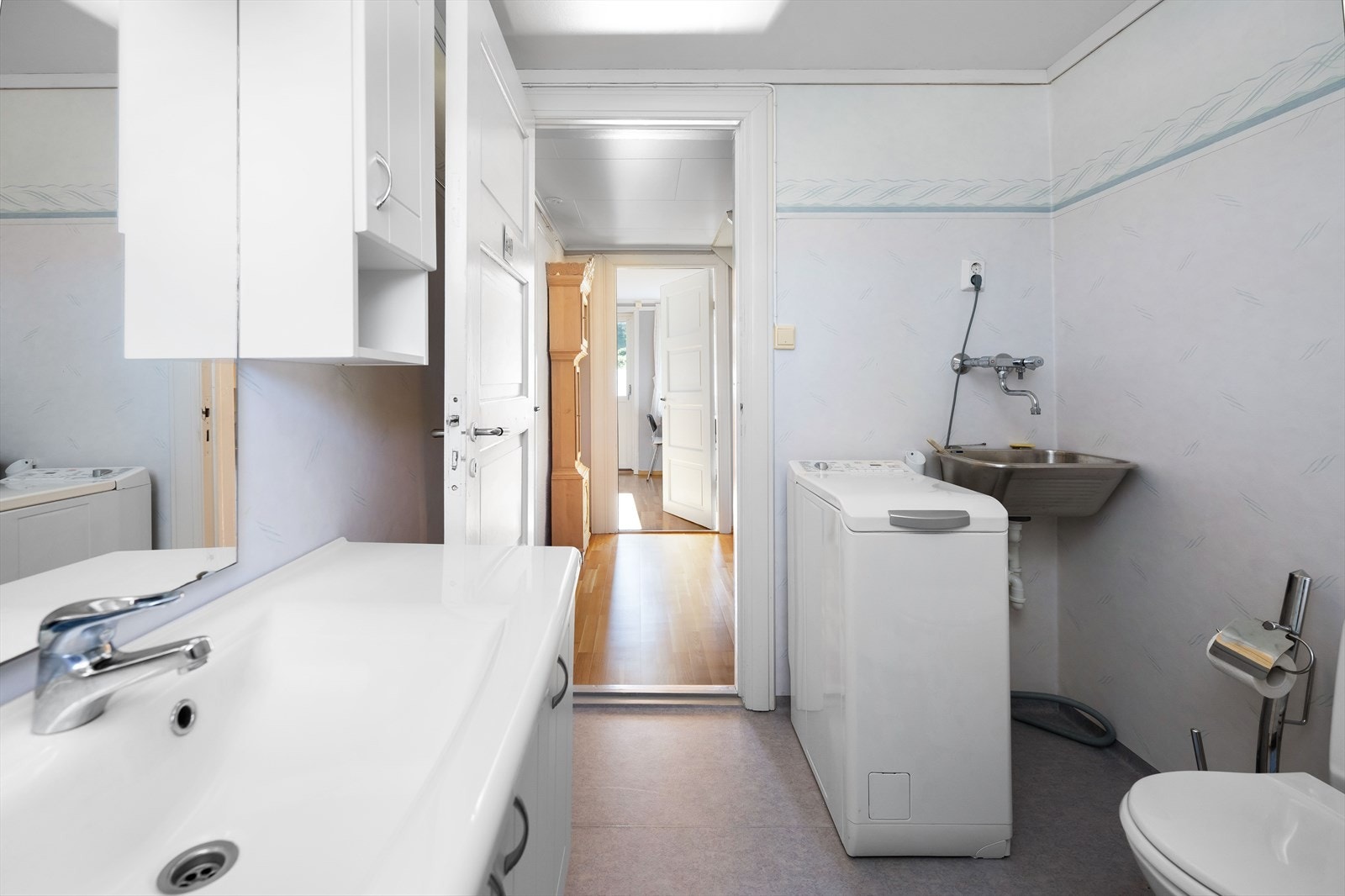 Det blitt plass for dusjkabinett, en innholdsrik baderomsinnredning med overskap og heldekkende servant, et frittstående toalett, plass for vaskemaskin samt et skyllekar. Galleribilde