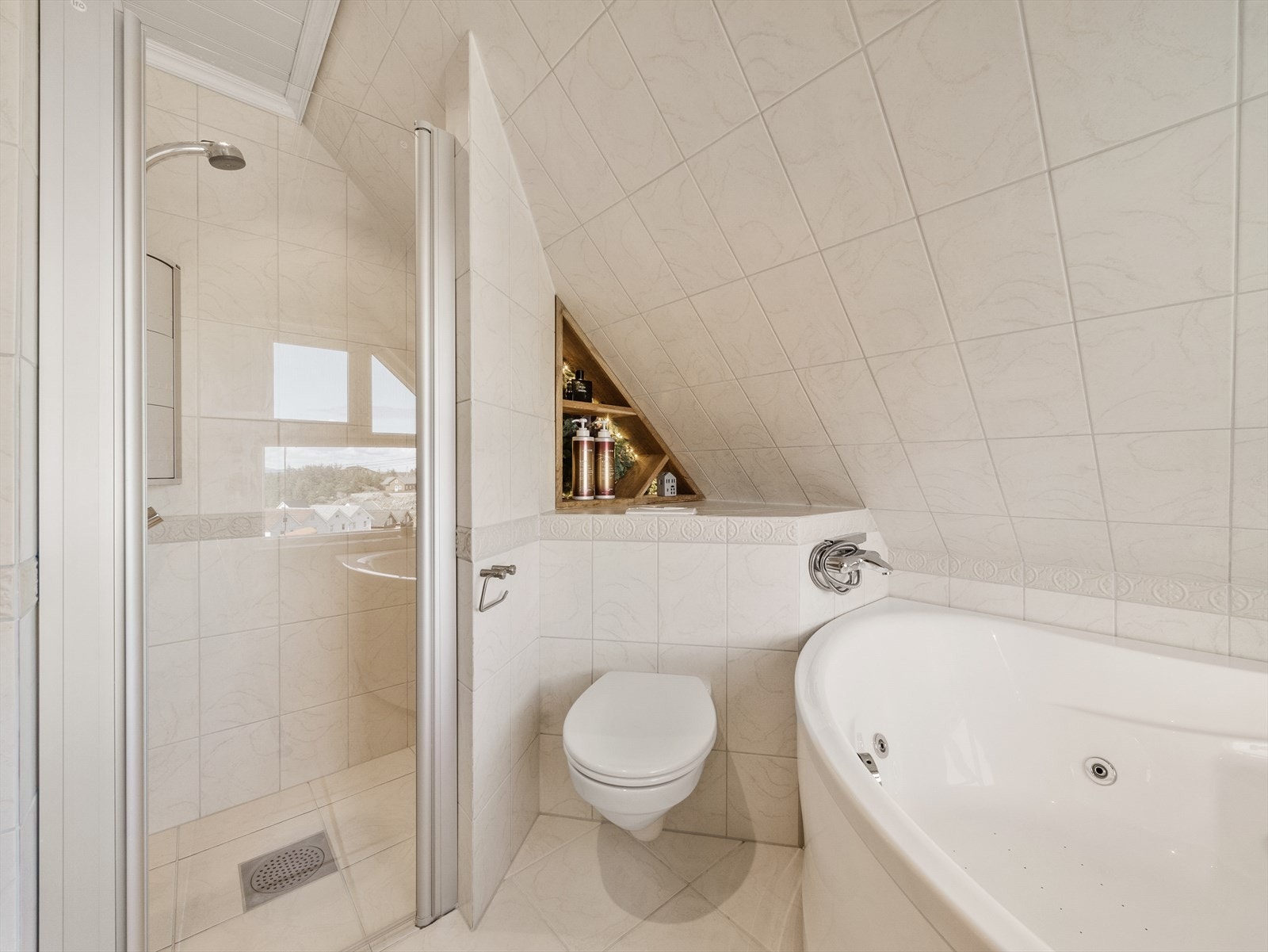 Badet er innredet med hjørnedusj-sone, vegghengt toalett, servant med innredning og boblebadekar. Galleribilde