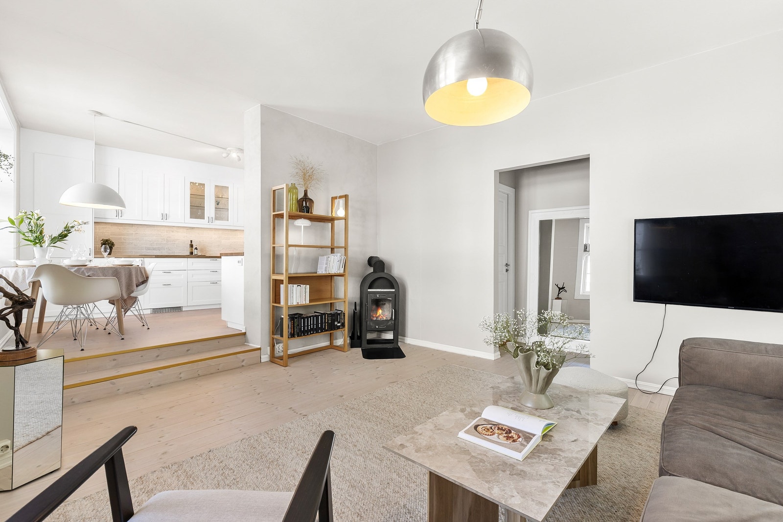 Den åpne løsningen skaper en luftig og åpen romfølelse, med direkte adkomst til kjøkkenet. På årets kjøligere dager luner det godt med en peis. Galleribilde