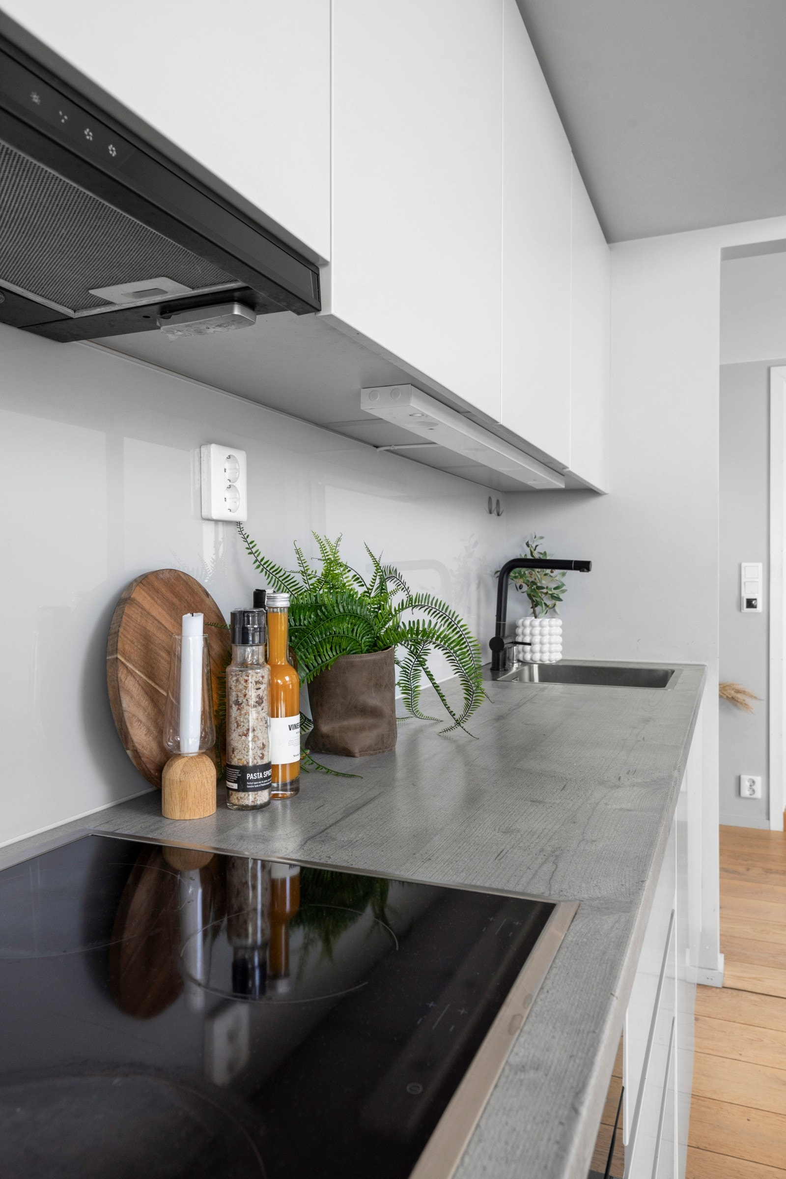 Innredningen har hvite, glatte fronter, herdet glassplate under overskap, benkebelysning og lysegrå benkeplate med stor oppvaskkum. Galleribilde