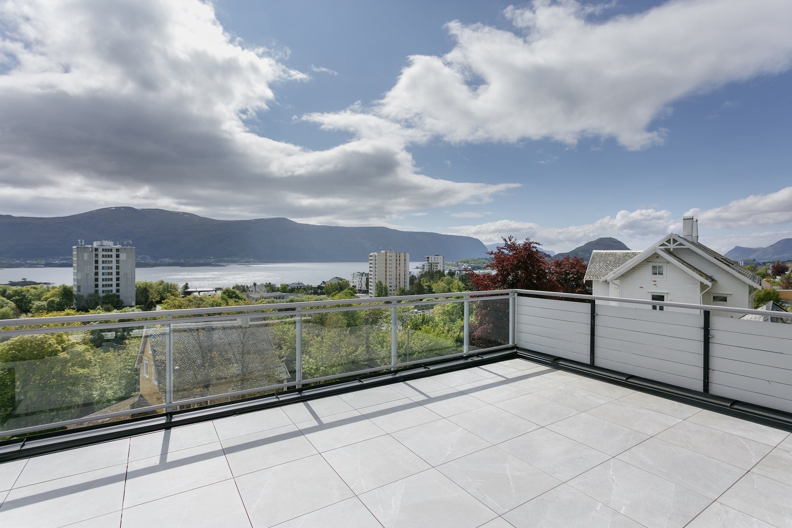 Stor sydvendt terrasse med fantastisk utsikt mot fjord og fjell og vestover mot Ålesund/Sukkertoppen fra eiendommen Galleribilde