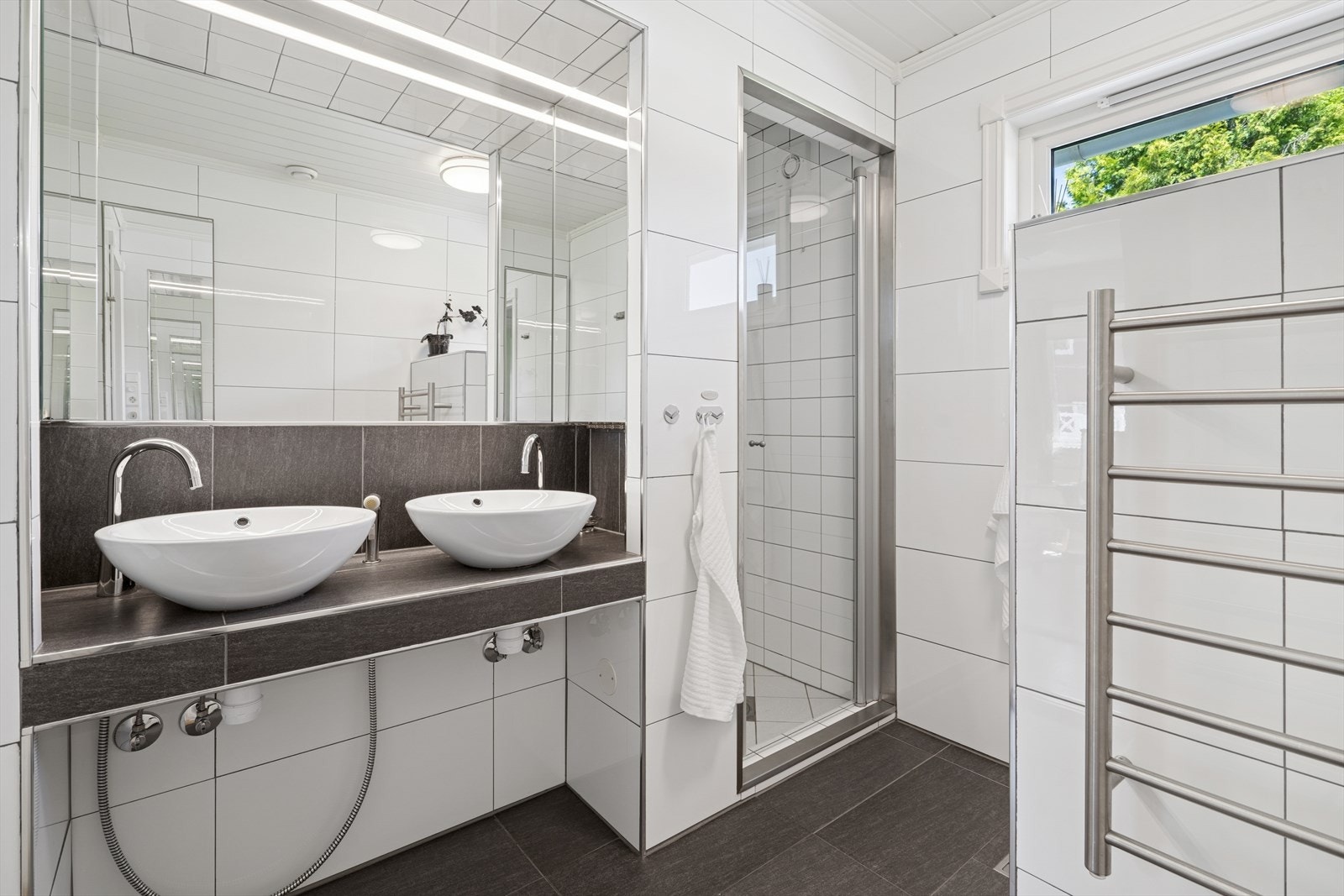 Rommet har plassbygget innredning med 2 servanter og skap, veggmontert toalett og dusjvegger/hjørne.
Det er mekanisk avtrekk. Galleribilde