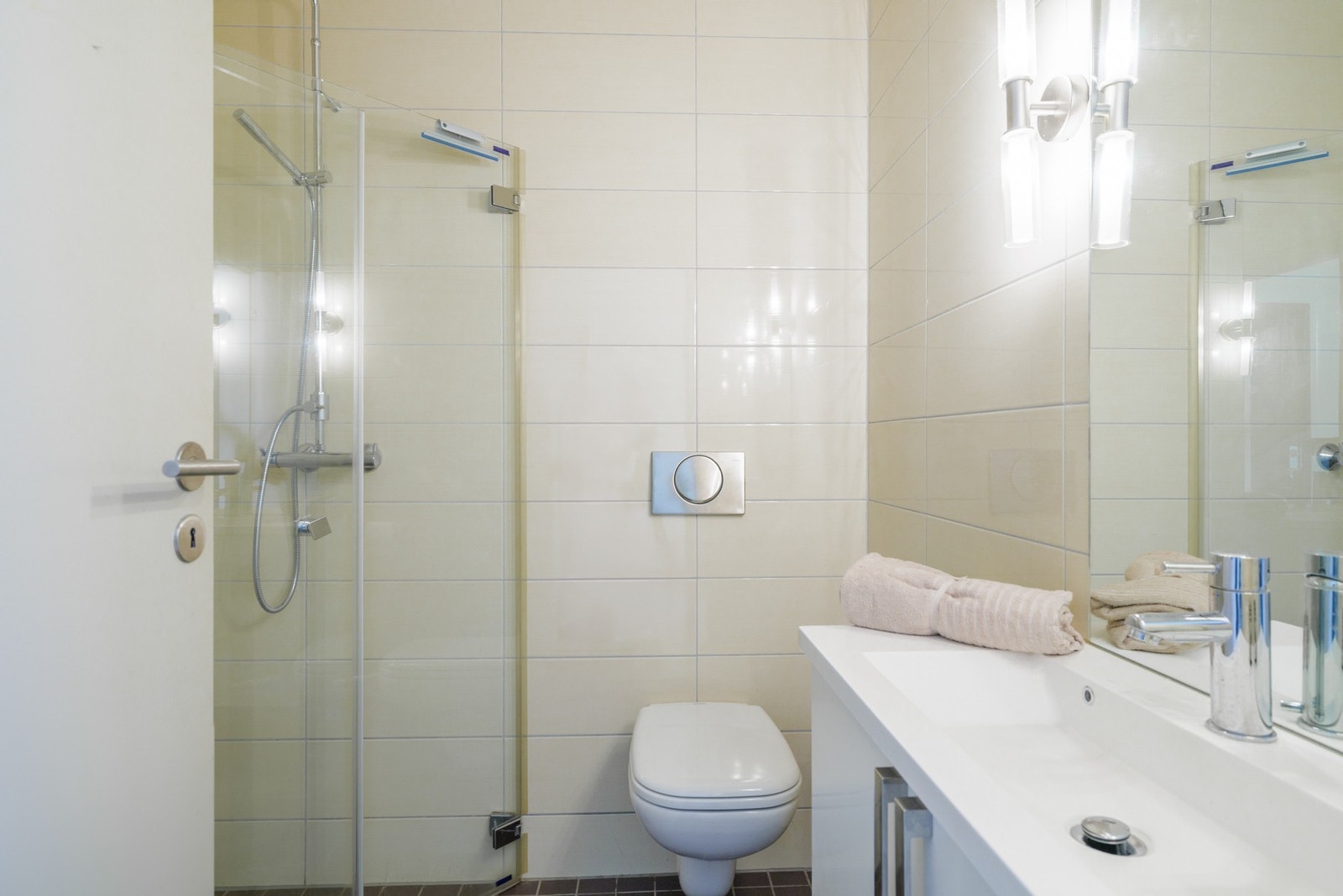 Badet er innredet med servantskap, speil med belysning, dusjhjørne med innfellbare glassdører med hånddusj og regndusj, vegghengt toalett med innebygd sisterne og opplegg for vaskemaskin. Galleribilde