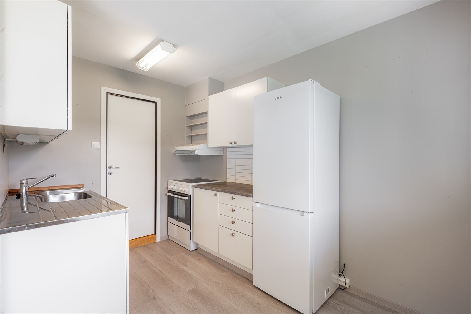 Benkeplate i laminat, oppvaskbenk i rustfritt stål. Over kokesonen er det montert kjøkkenventilator med avtrekk ut. Galleribilde