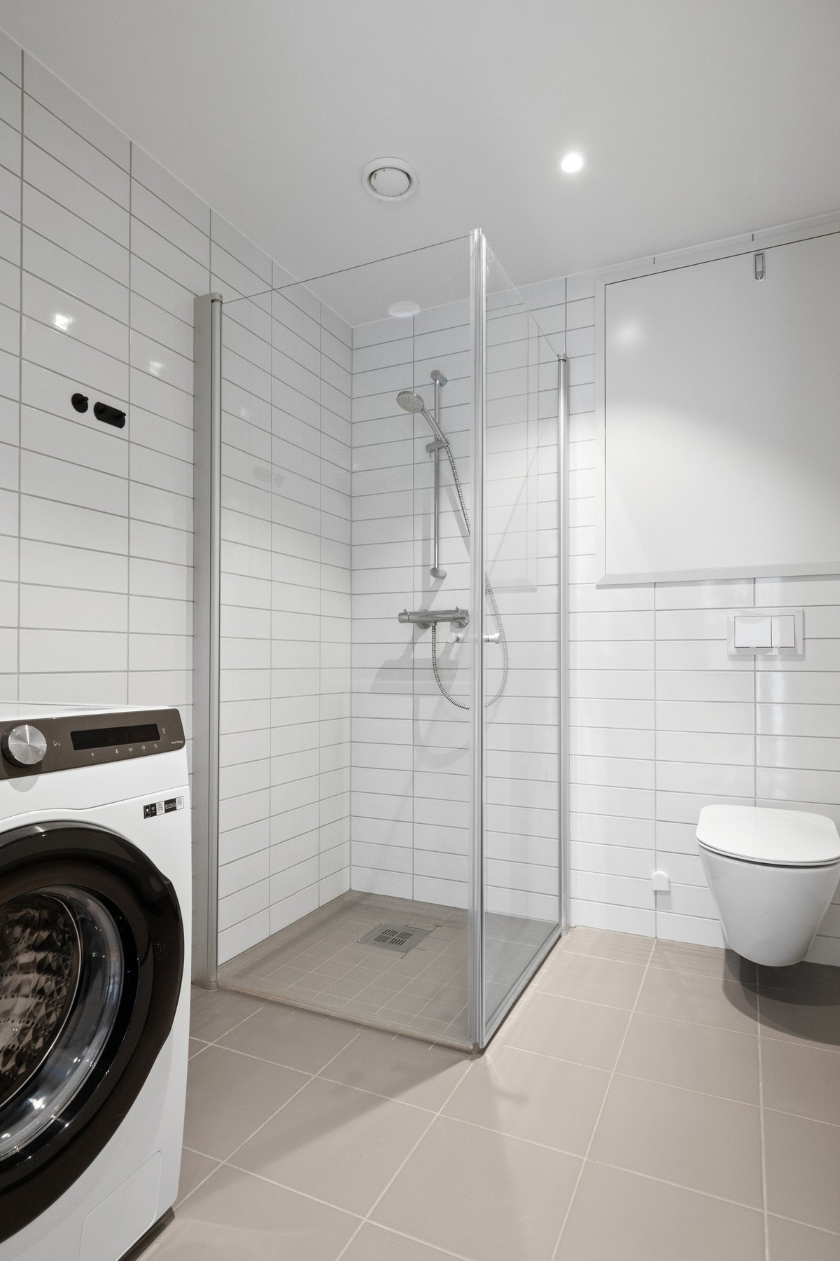 Badet fremstår som delikat og moderne, med hvite veggfliser og lysegrå gulvfliser. Galleribilde