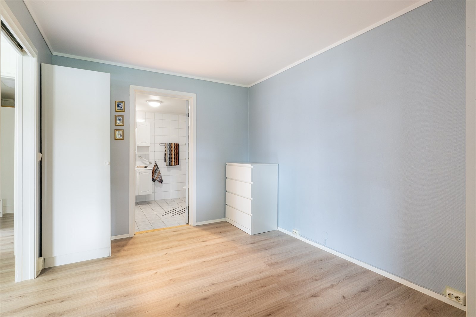 Romslig soverom med laminat på gulvet, malt glassfiberstrie på veggene og pusset, malt betong i taket. Galleribilde