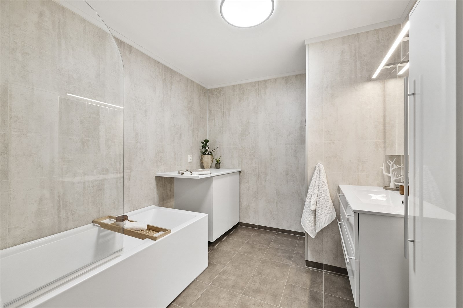 Badet er praktisk innredet med blant annet badekar med dusjopplegg og vegghengte skap for god oppbevaring. Galleribilde