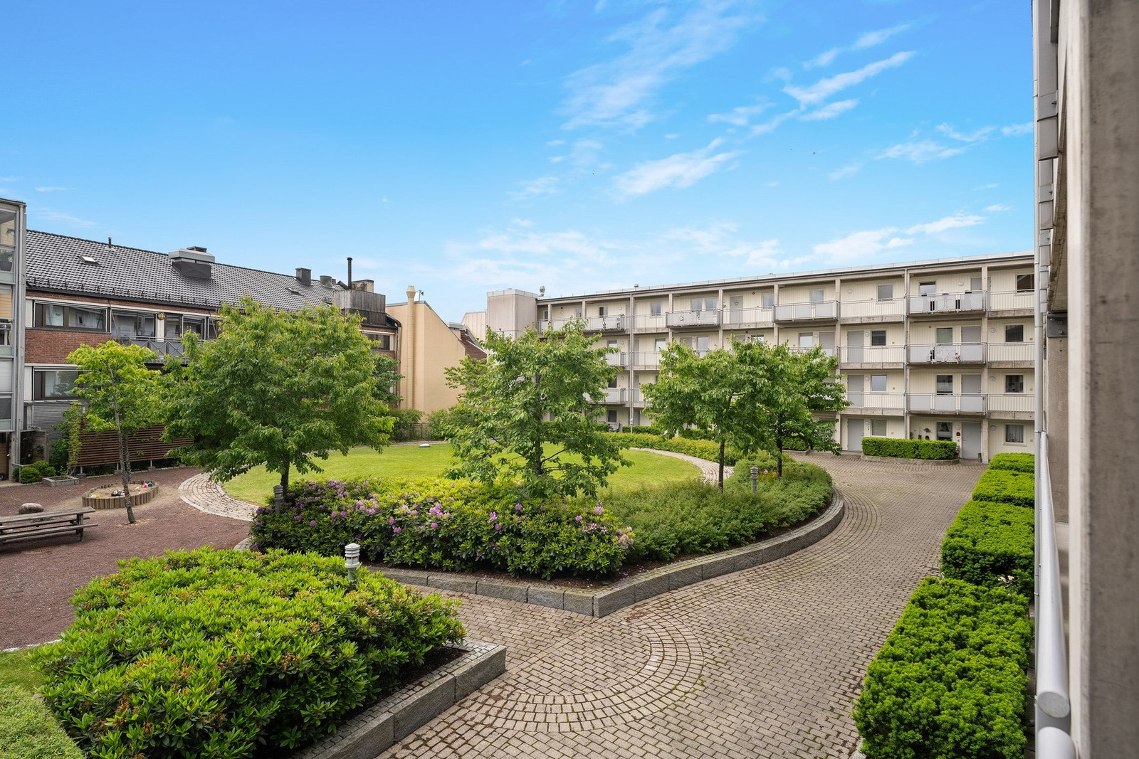 Felles gårdsrom med beplantning, benker og brostein. Galleribilde