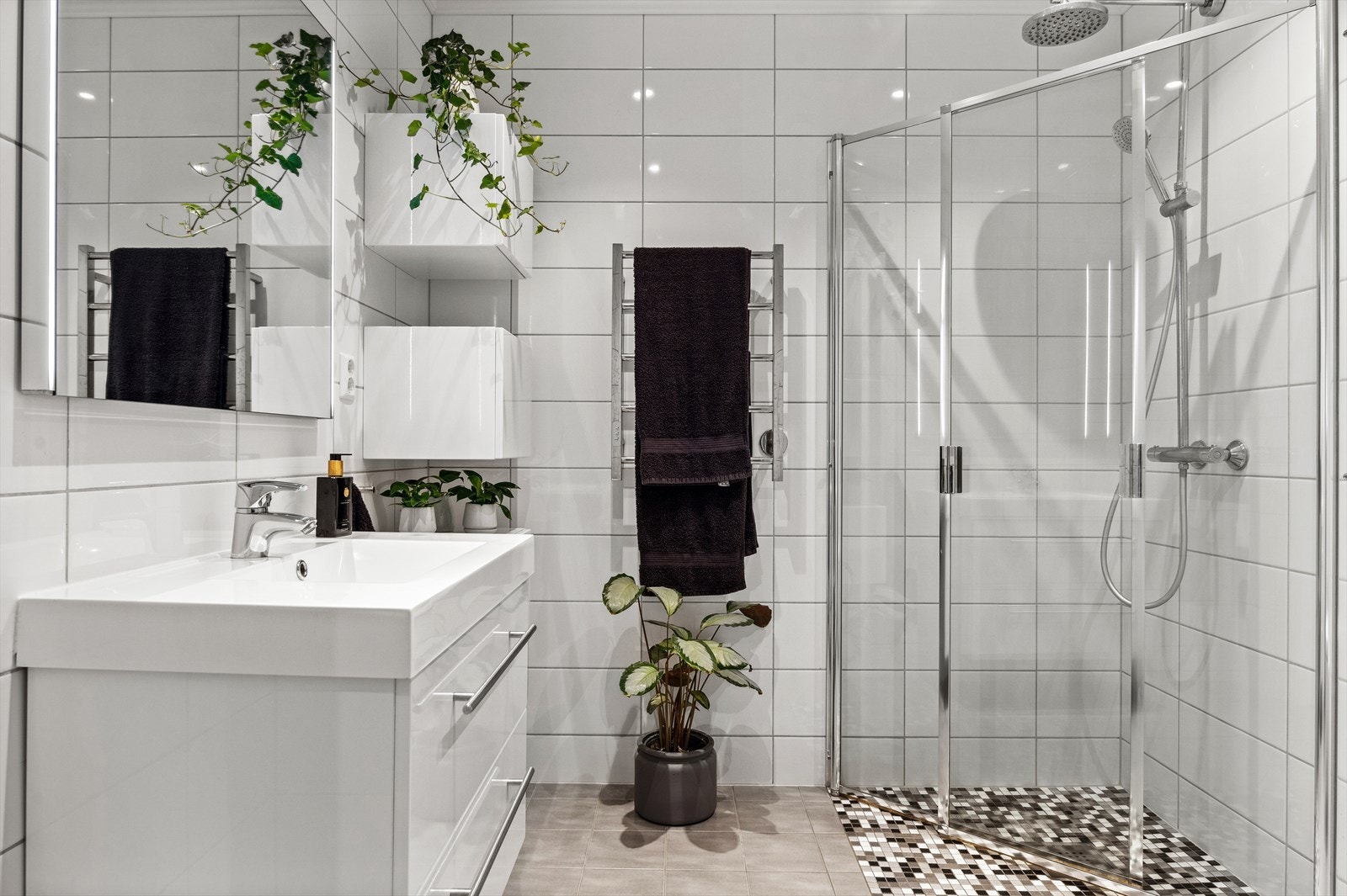 Badet i 1. har baderomsinnredning med skuffer, servant og veggskap med glatte fronter i høyglanset utførelse. Dusj med innfellbare dører i herdet glass og veggfestet klosett med innebygget sisterne. Galleribilde