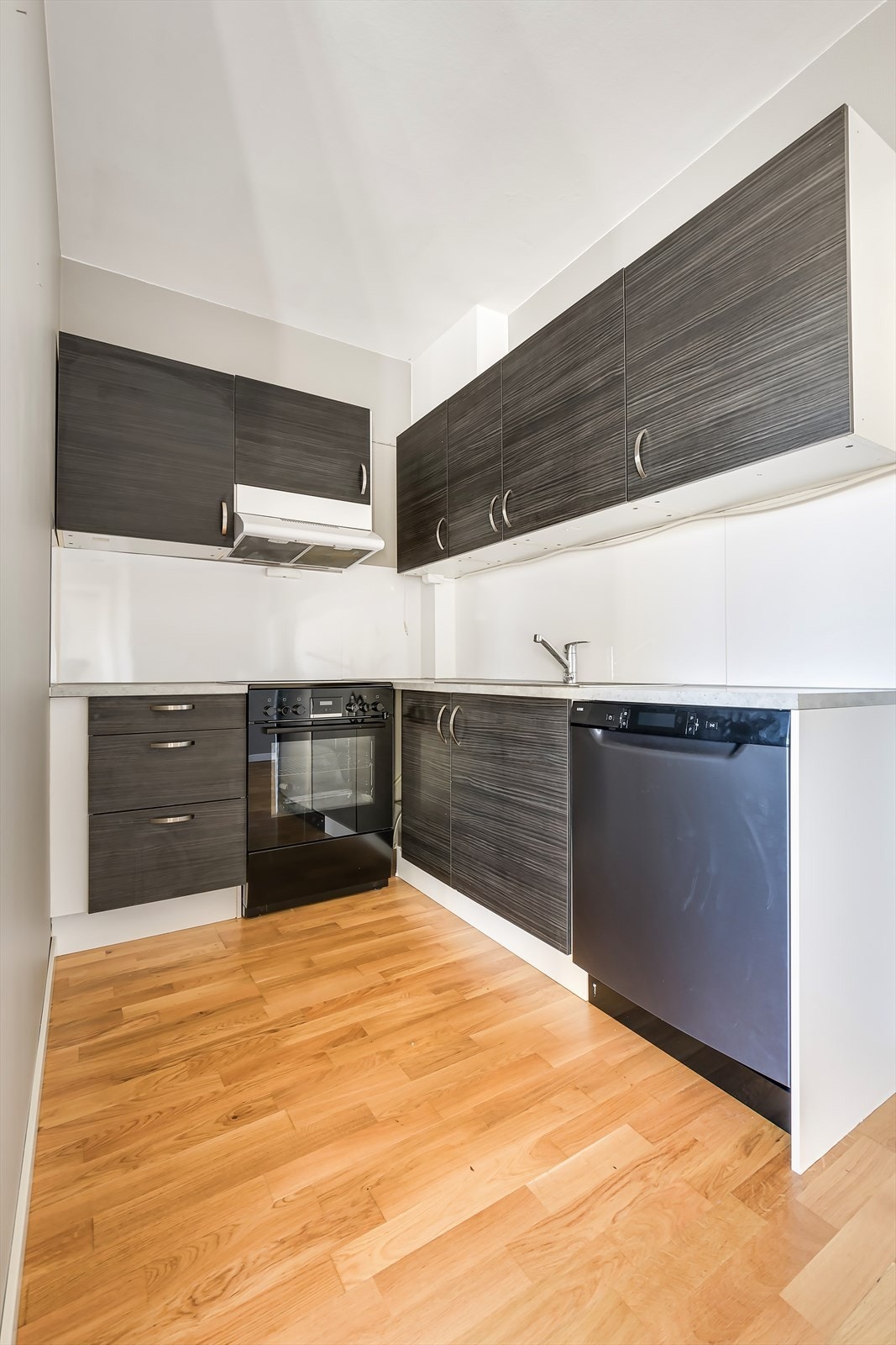 Kjøkkeninnredning med mørke, glatte fronter og benkeplate av laminat. Galleribilde