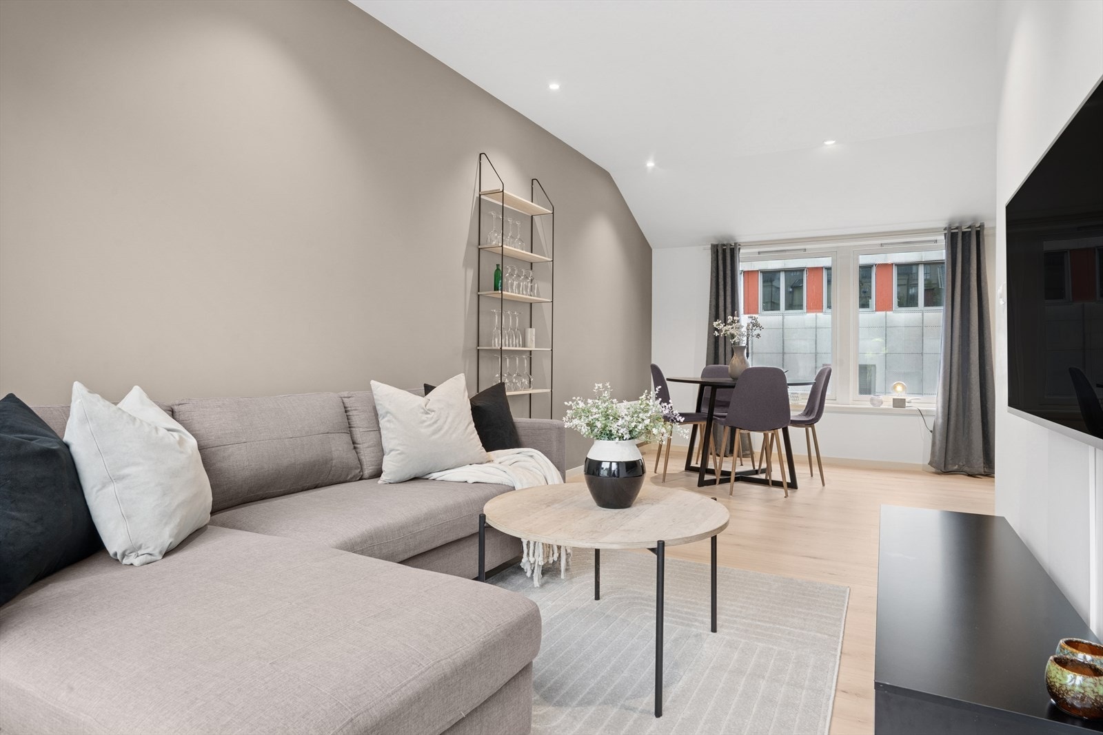 En moderne og flott stue med lyse, listefrie overflater og downlights i tak Galleribilde