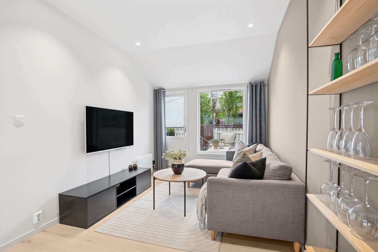 En moderne og flott stue med lyse, listefrie overflater og downlights i tak Galleribilde