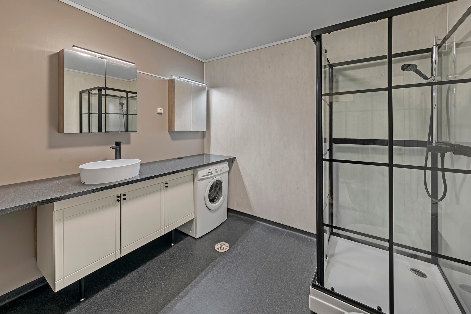 Badet har vinylbelegg på gulv med elektriske varmekabler. Baderomsinnredning med servant og benkeplate i laminat. Dusjkabinett og gulvmontert toalett Galleribilde