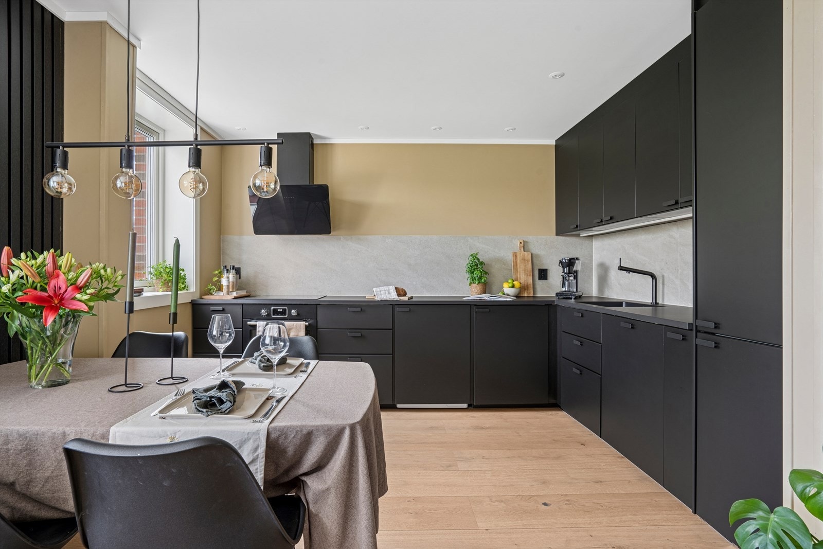 Spisebordet ligger midt mellom stuen og kjøkkenet - spileveggen lager naturlige soner Galleribilde