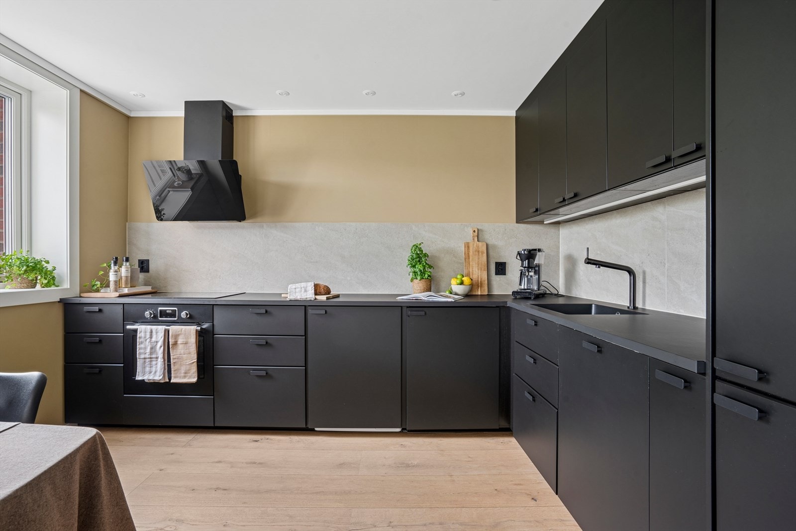 Kjøkkeninnredningen er takhøy med slette fronter og integrerte hvitevarer Galleribilde