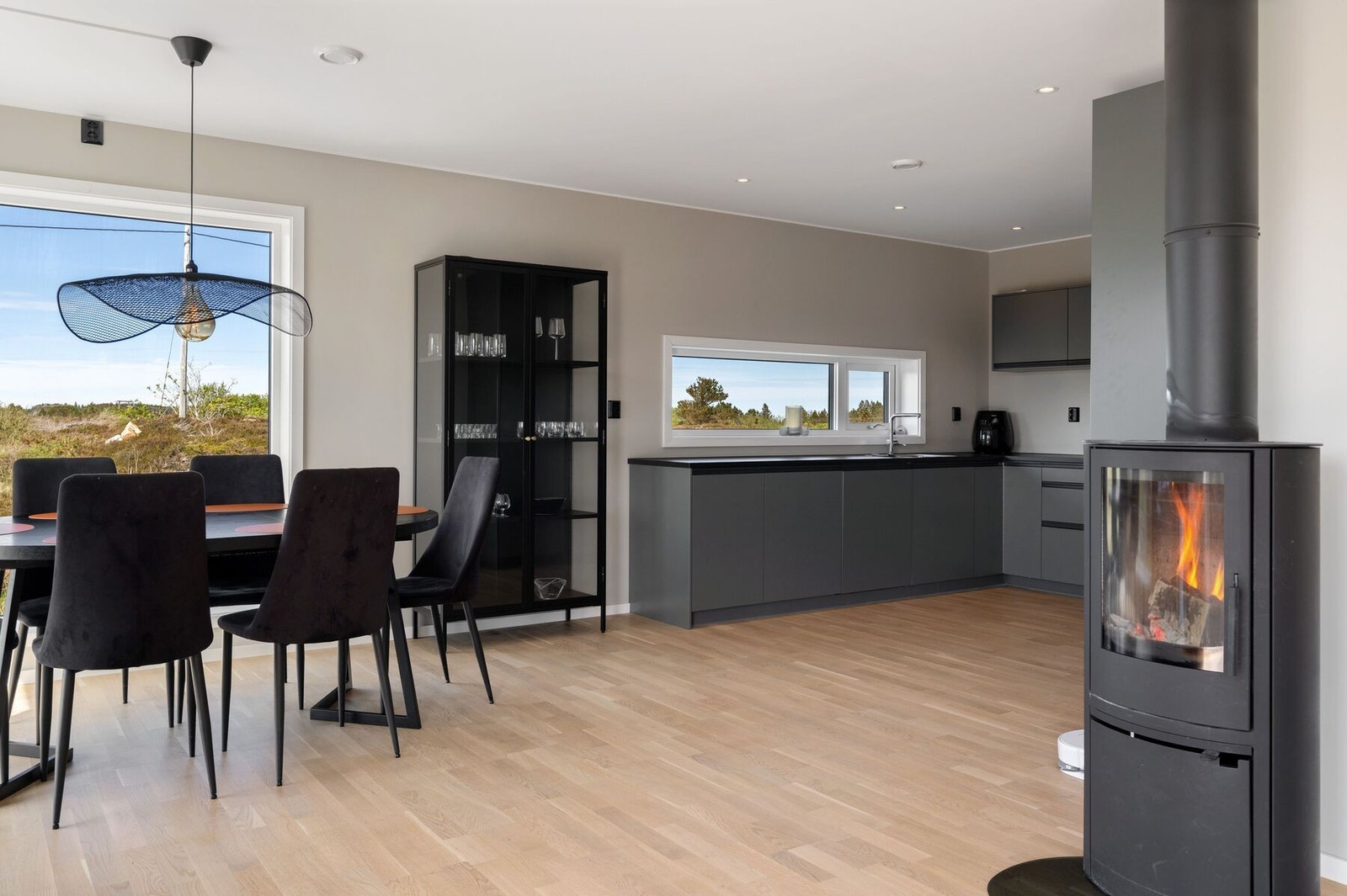 Vedovn i skille mellom stue og kjøkken skaper koselig atmosfære, samtidig som det er en fin oppvarmingskilde Galleribilde