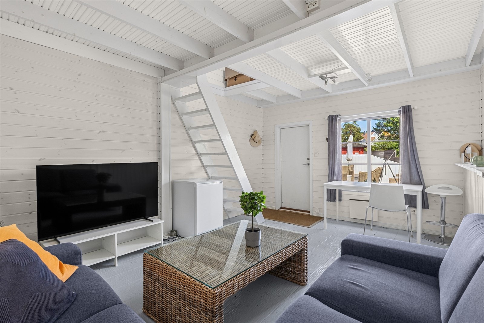 Hagestuen er innredet med sofagruppe, skrivebord og tv. Galleribilde