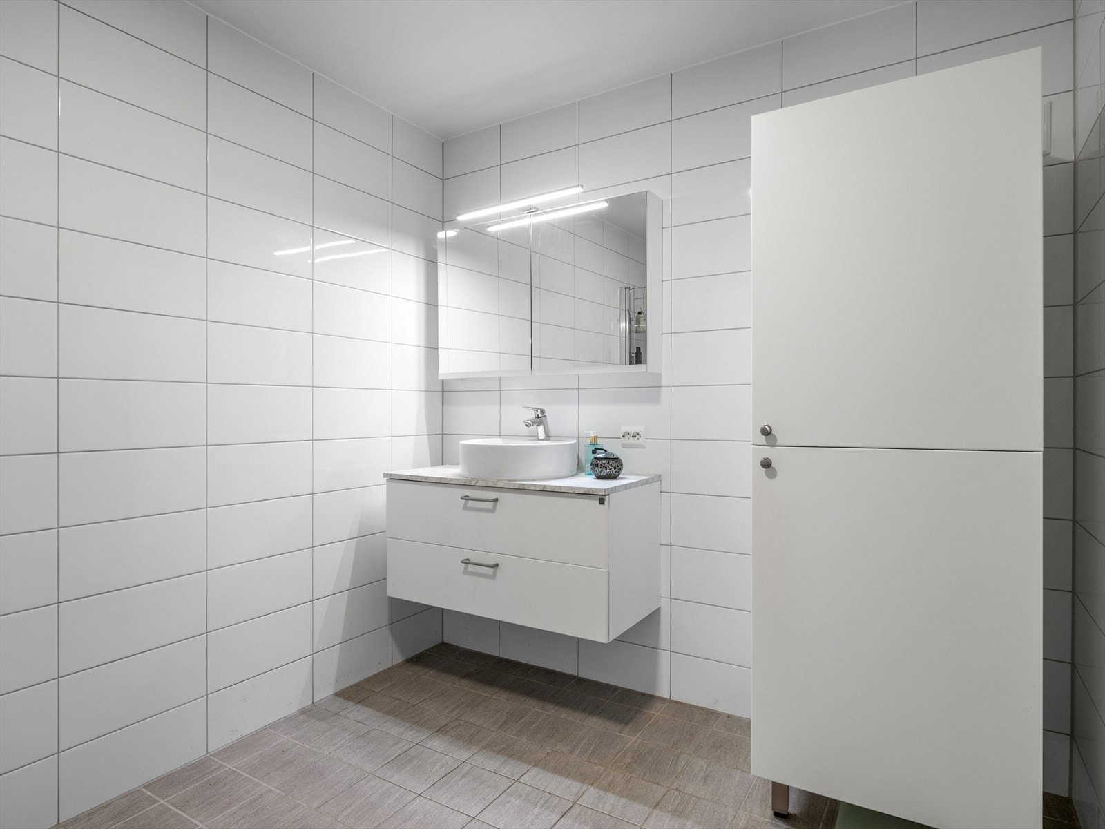 Moderne, lyst baderom med stilrene fliser og praktisk innredning. Perfekt for et stilrent og funksjonelt hjem. Galleribilde