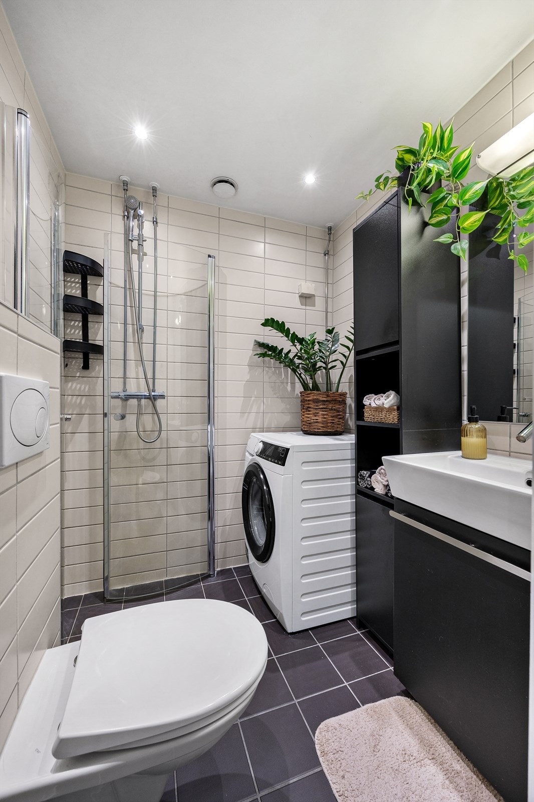 Baderommet er utstyrt med dusj på gulv med dører i herdet glass, servant og veggfestet klosett med innebygget sisterne. Galleribilde