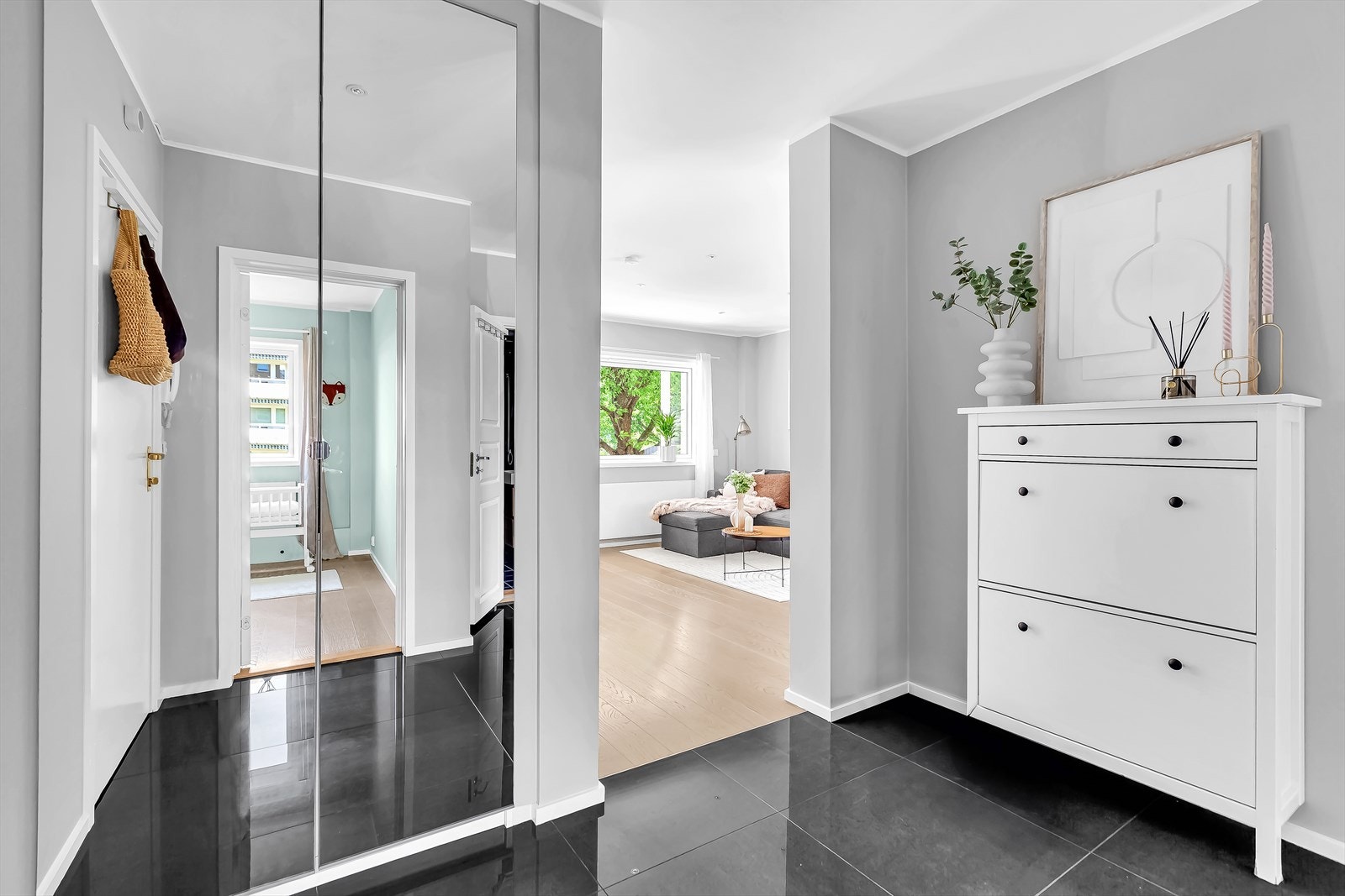 Yttertøy og sko ryddes pent bort i et garderobeskap med speilfronter. Galleribilde