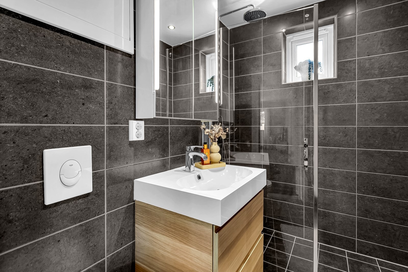 Rommet har i tillegg plassbesparende løsninger som dusjhjørne med glassdør, frittstående toalett, servant med underskap, speilskap med belysning og høyskap. Galleribilde