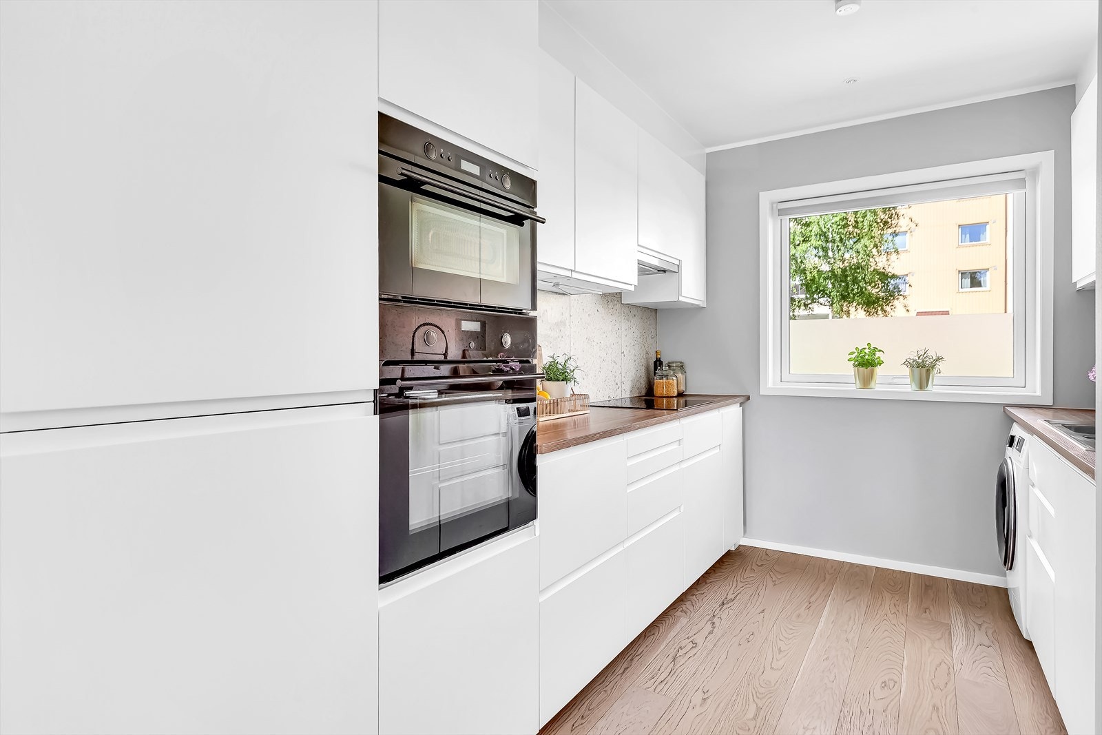 Plassbesparende og integrerte hvitevarer som induksjonstopp, stekeovn, mikrobølgeovn, oppvaskmaskin og kjøleskap med frysedel. Galleribilde