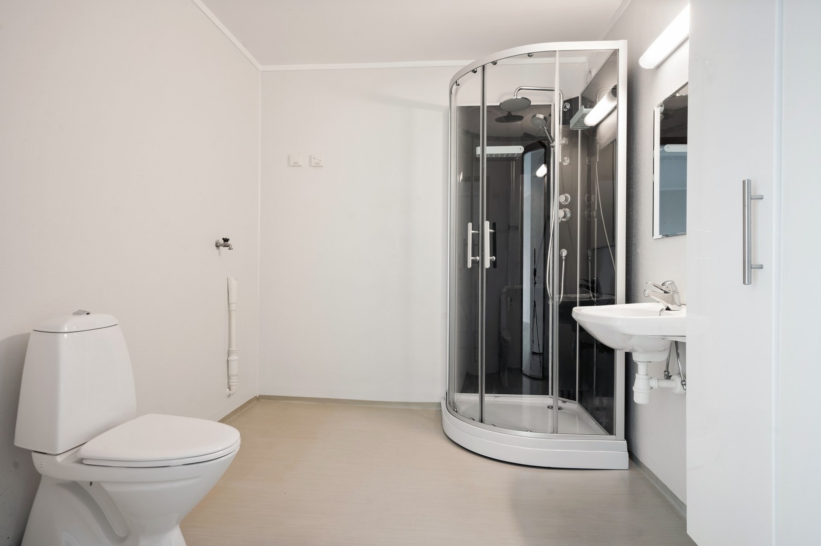 Badet er innredet med gulvstående wc (2025) , servant, høyskap, dusjkabinett (2022) og opplegg for vaskemaskinvaskemaskin. Galleribilde