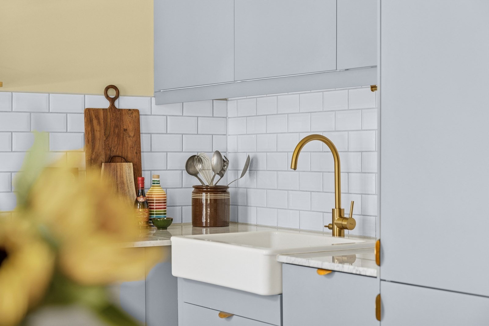 Benkeplate i marmor, utstyrt med kjøkkenkran i messing og vaskekum i keramikk. Galleribilde