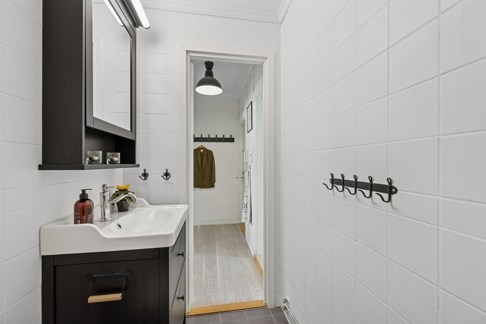 Badet er utstyrt med frittstående klosett, dusj på vegg med forheng og servant med tilhørende underskap. Det er et overskap med speil over servanten. Galleribilde