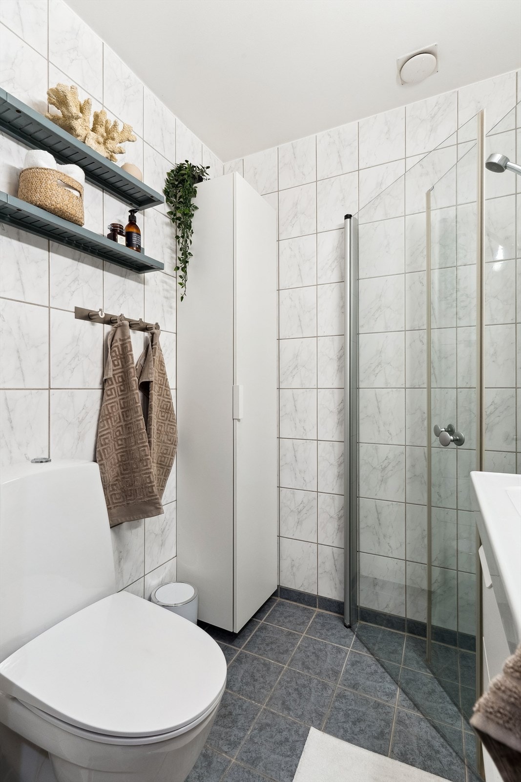 Badet er smart innredet med toalett, dusj og plass til oppbevaring. En gjennomført løsning som kombinerer funksjon og stil på liten flate. Galleribilde