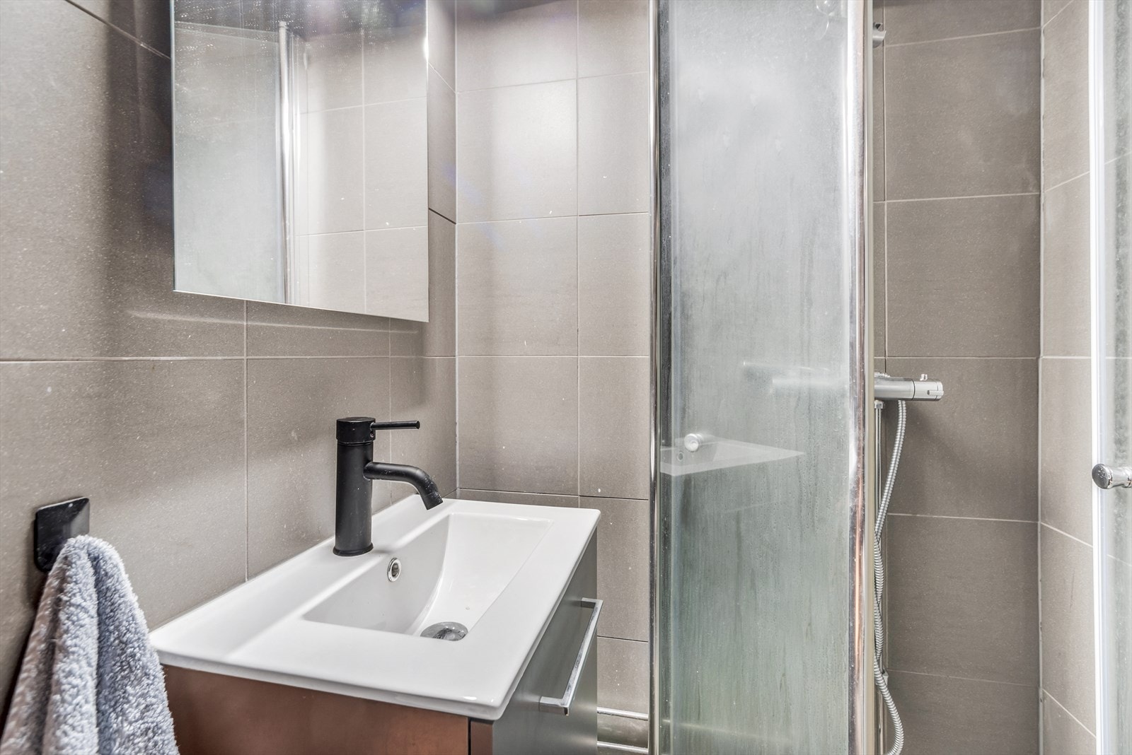 Flislagt bad med moderne dusj og servant. Praktisk og stilrent design for en komfortabel hverdag. Galleribilde