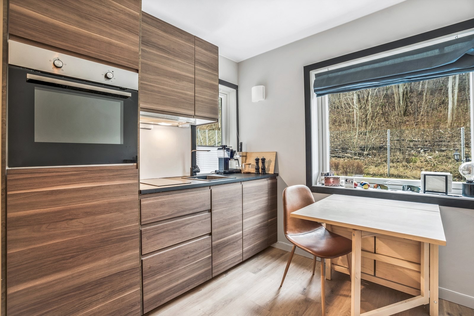 Lyst og moderne kjøkken med stilrene, tredekkede flater og store vinduer som gir rikelig med naturlig lys. Galleribilde