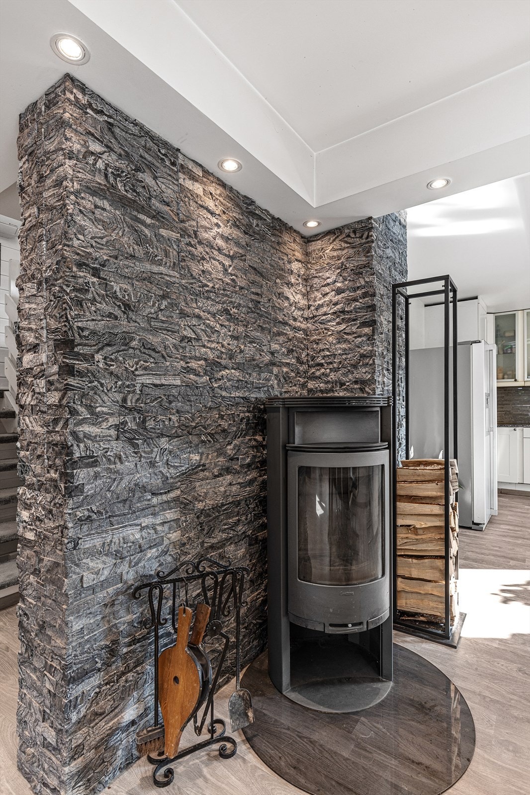 Den koselige peisen er strategisk plassert i overgangen mellom kjøkkenet og stuen og varmer godt på kalde vinterdager Galleribilde