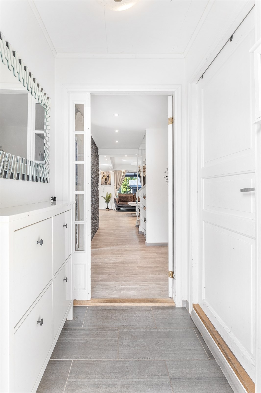 Velkommen inn! Lys entré med flislagt gulv og malte overflater. I entreen er det montert et praktisk vegghengt skoskap Galleribilde