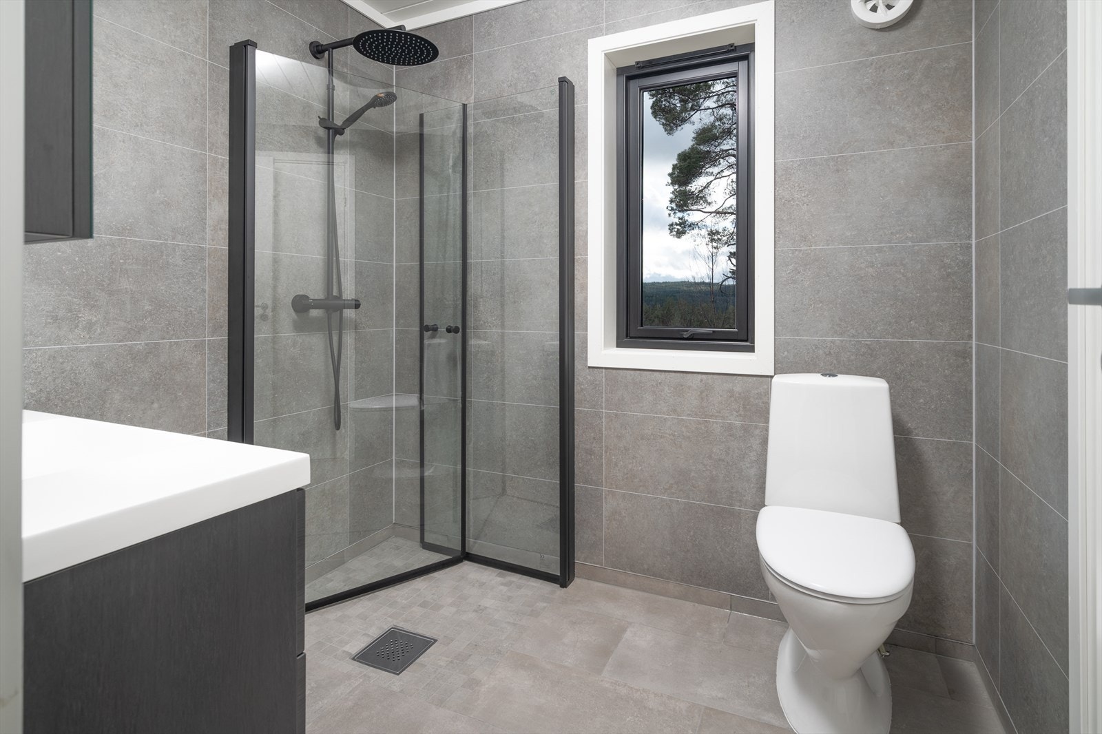 Smakfullt bad med fliser, varmekabler og sorte detaljer Galleribilde