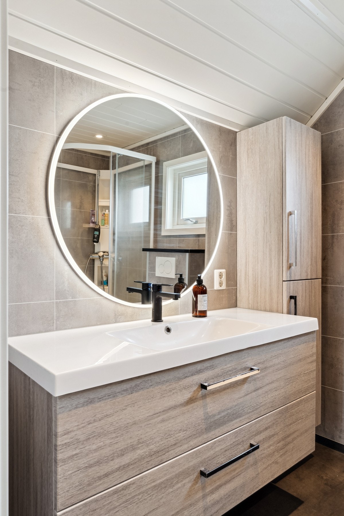 Våtrommet har innredning med heldekkende servant og ett-greps blandebatteri, vegghengt speil med lys, vegghengt toalett og dusjkabinett. Galleribilde