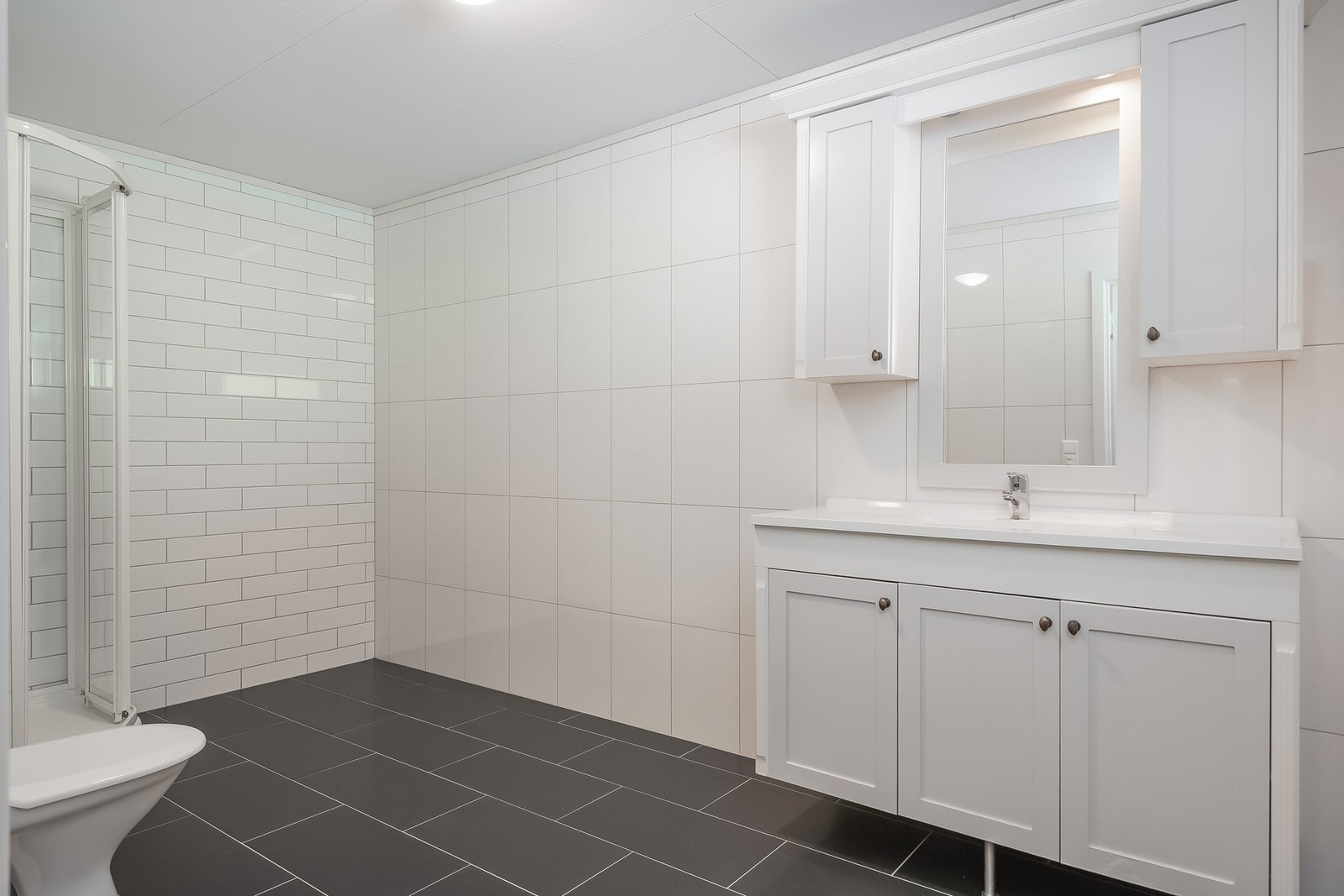 Flott og romslig bad som ble pusset opp i 2018. Badet måles til 9 kvm, og er innredet med dusjkabinett. gulvmontert toalett, og servant med underskap. Galleribilde