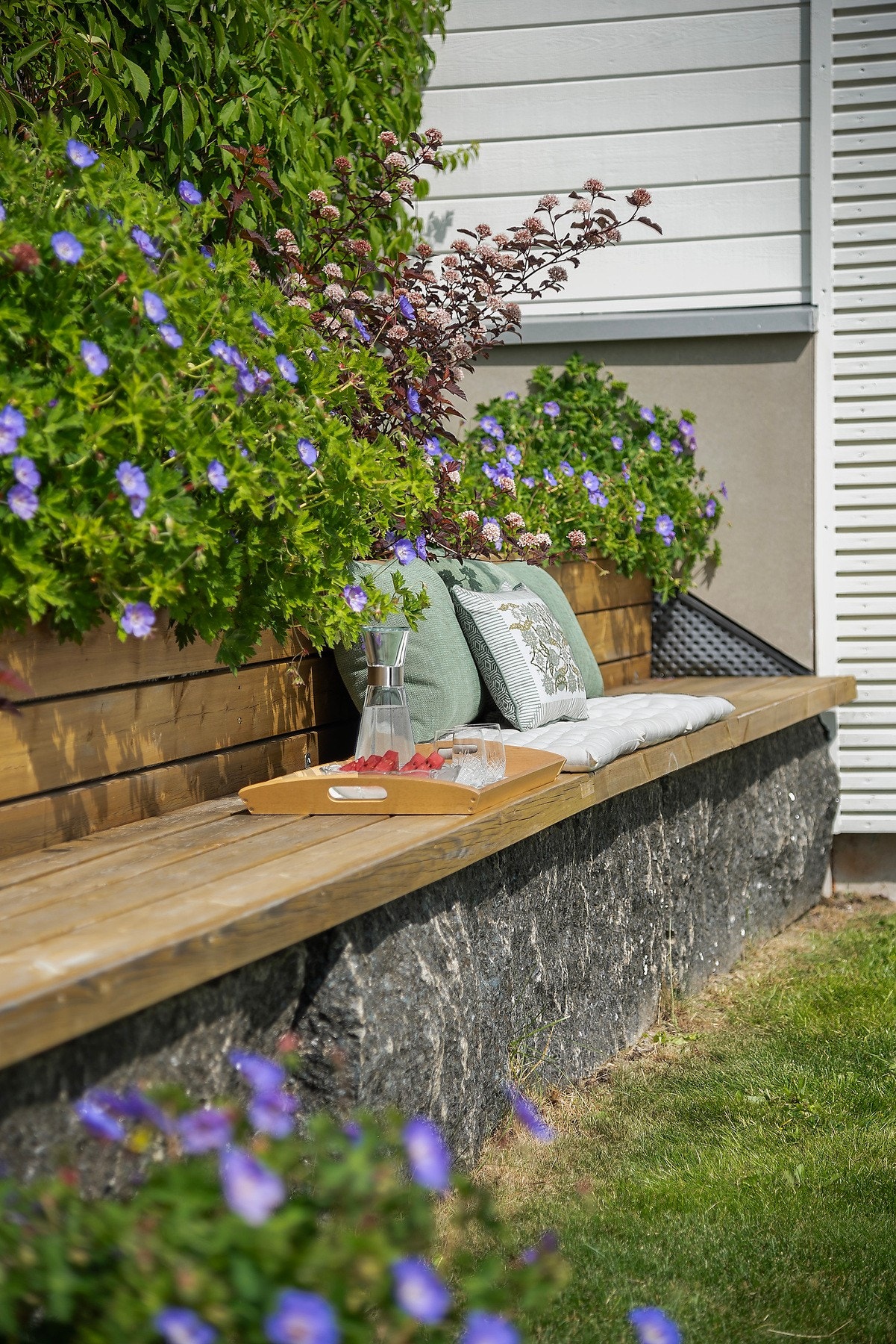 Det er bygget en ekstra benk langs blomsterbedet - et koselig og praktisk innslag som inviterer til å nyte hagen Galleribilde