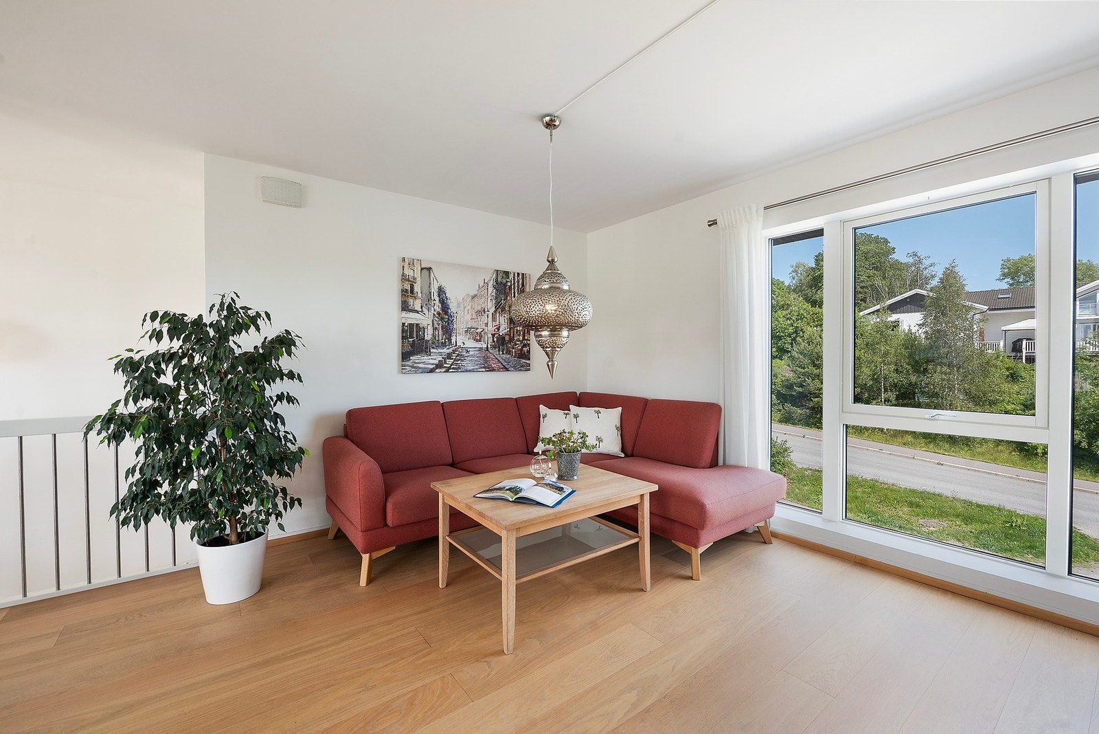 Stuen har lyse, nøytrale farger og et flott lysinnslipp gjennom store vinduer fra gulv til tak Galleribilde