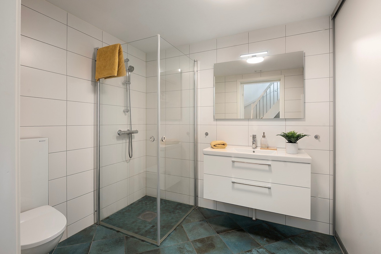 Badet i etasjen er innredet med vegghengt toalett, dusjhjørne og servant i innredning med skuffer Galleribilde