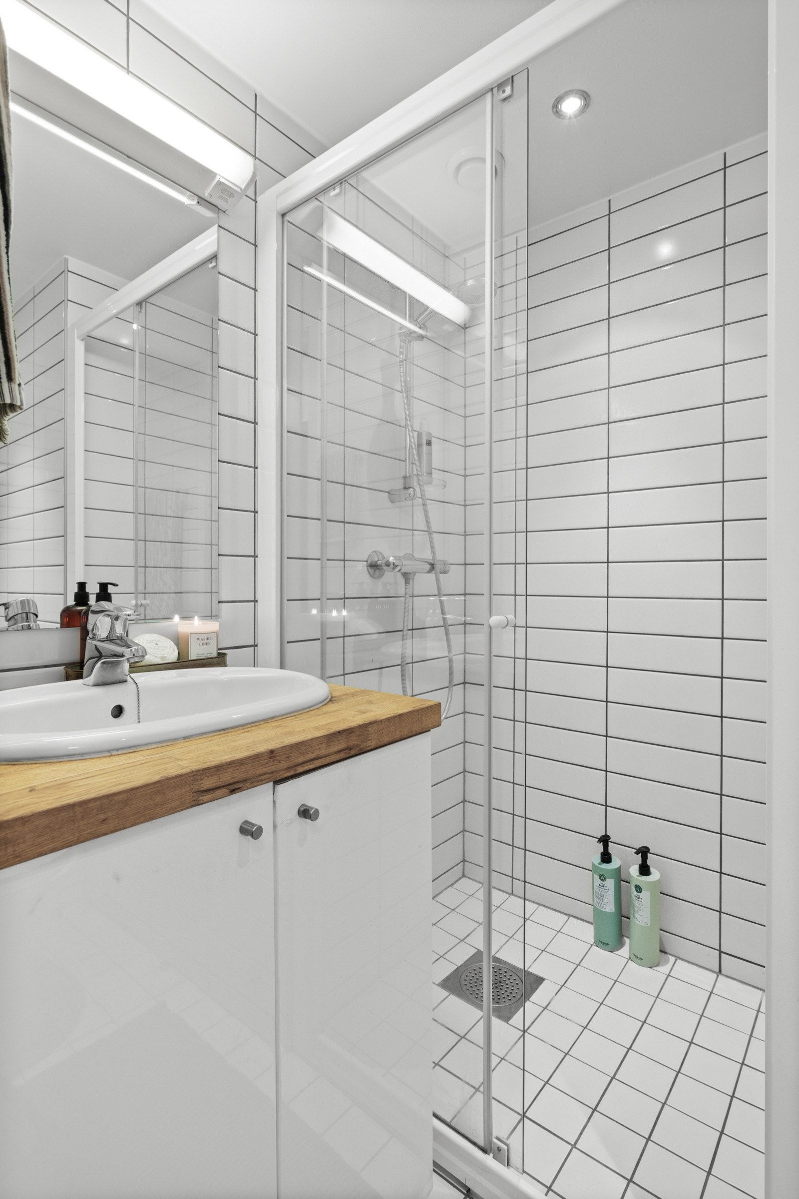 Det flislagte badet er innredet med slett lys innredning med servant og underskap samt ettgreps blandebatteri, toalett og dusjnisje med skyvedører i glass. Galleribilde