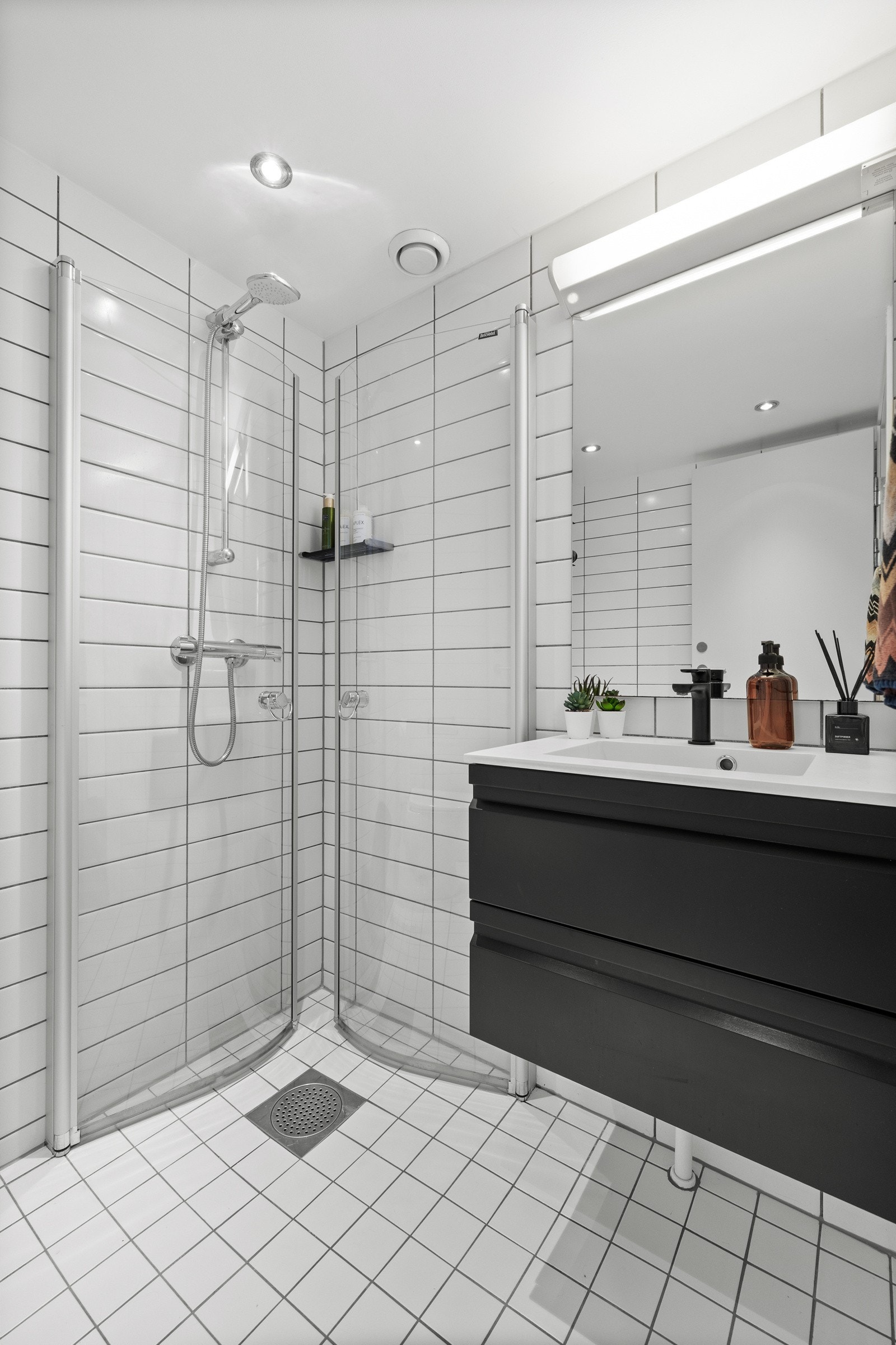 Det flislagte badet er fra 2006 og er innredet med slett mørk servantmøbel med skuffer, servant og ettgreps blandebatteri, toalett og dusjnisje med innfellbare dører i glass. Galleribilde