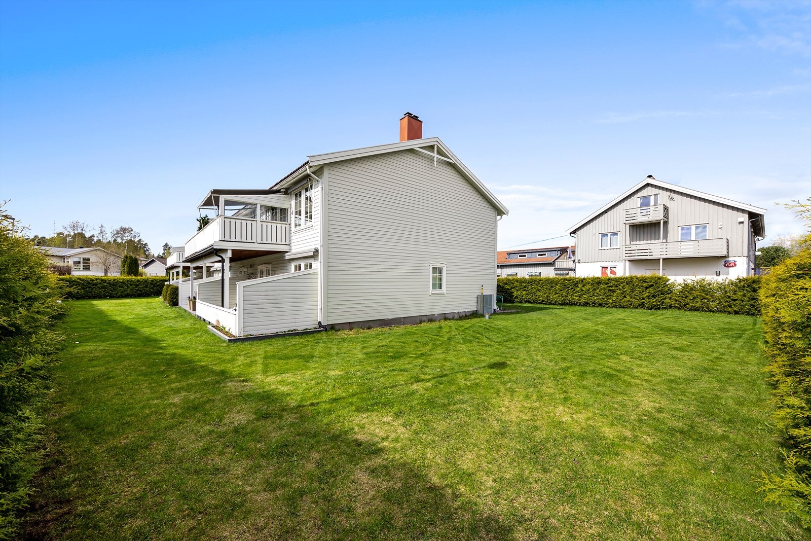 Flat felles tomt for sameiet som er pent opparbeidet og beplantet med plen, trær og busker. Galleribilde