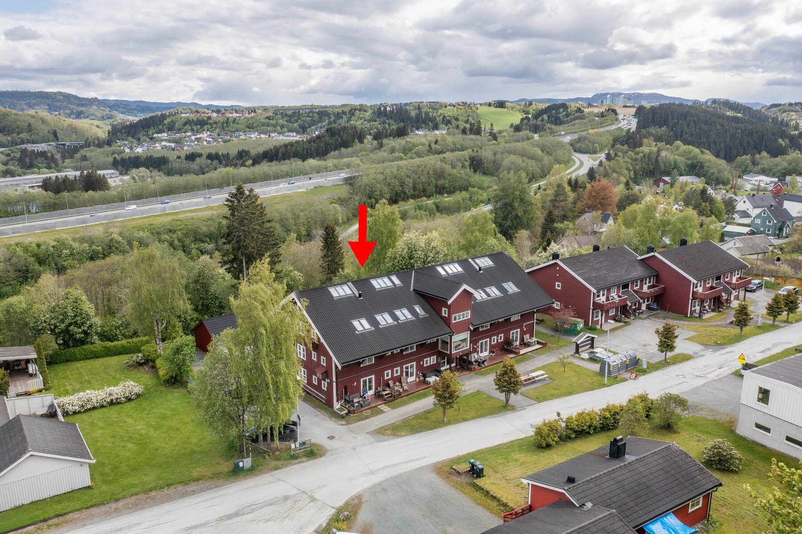 Dronefoto. Borettslagets fellesområder og fasade. Rød pil markerer leilighetens plassering i bygget. Galleribilde