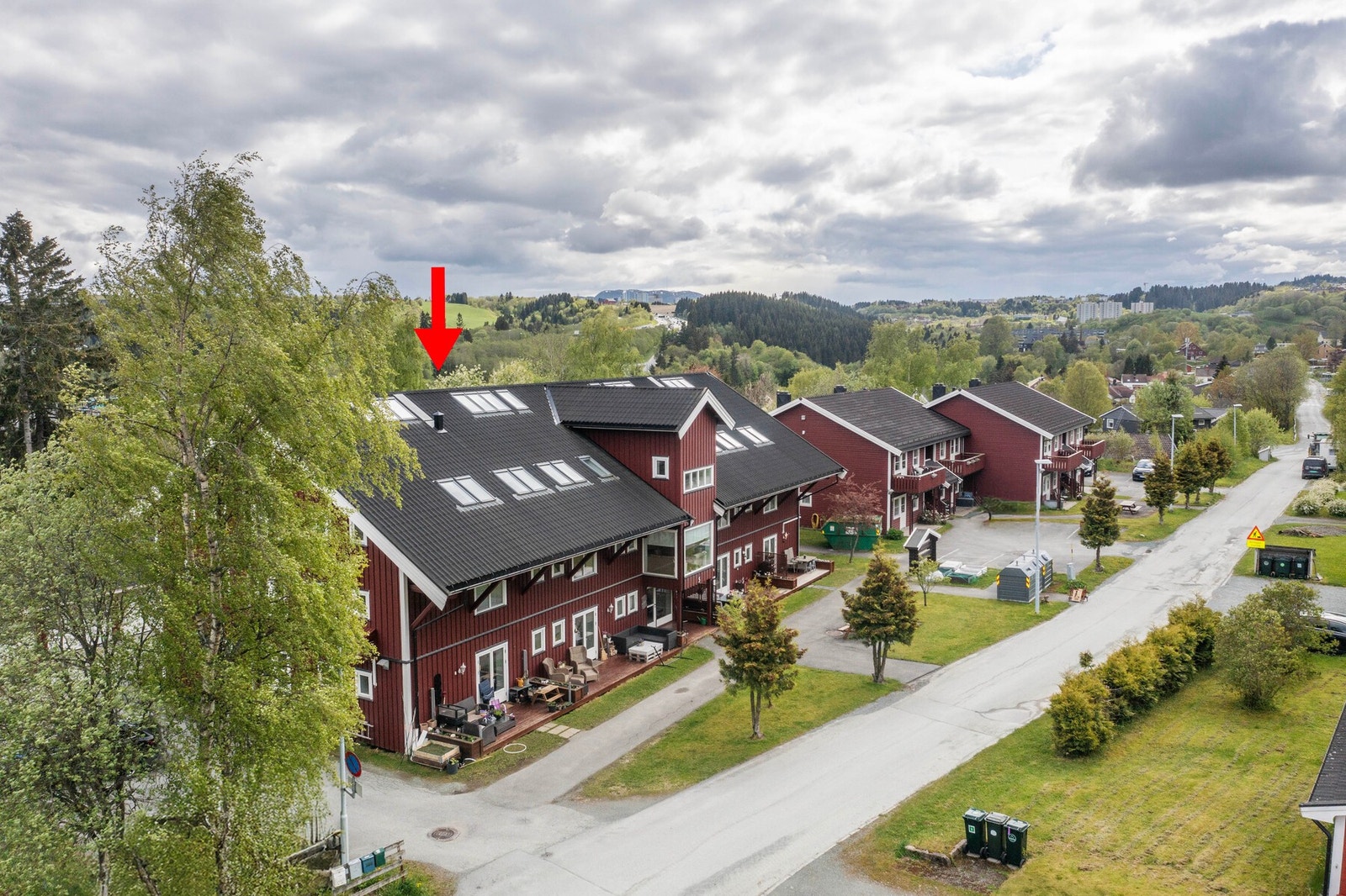 Dronefoto. Borettslagets fellesområder og fasade. Rød pil markerer leilighetens plassering i bygget. Galleribilde