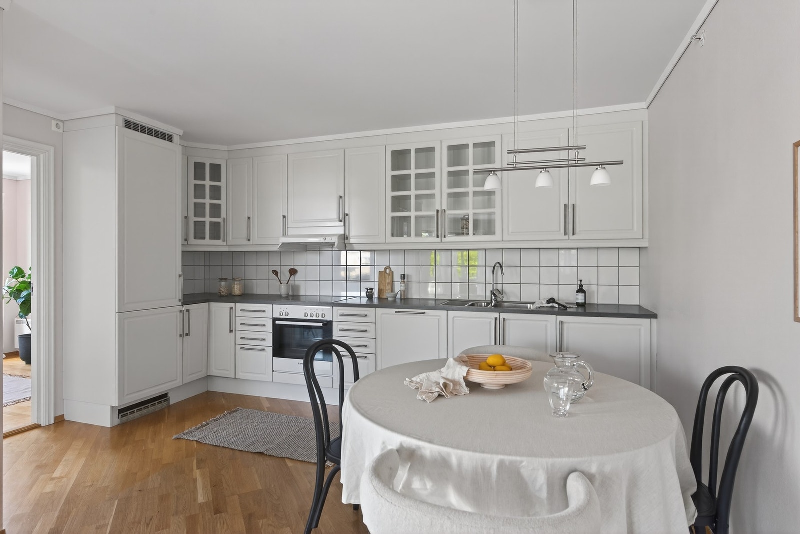 Kjøkkenet er fullt utstyrt med integrerte hvitevarer som kjøl/frys, stekeovn, platetopp og oppvaskmaskin - og de delikate vitrinedørene gir rommet et myktuttrykk Galleribilde