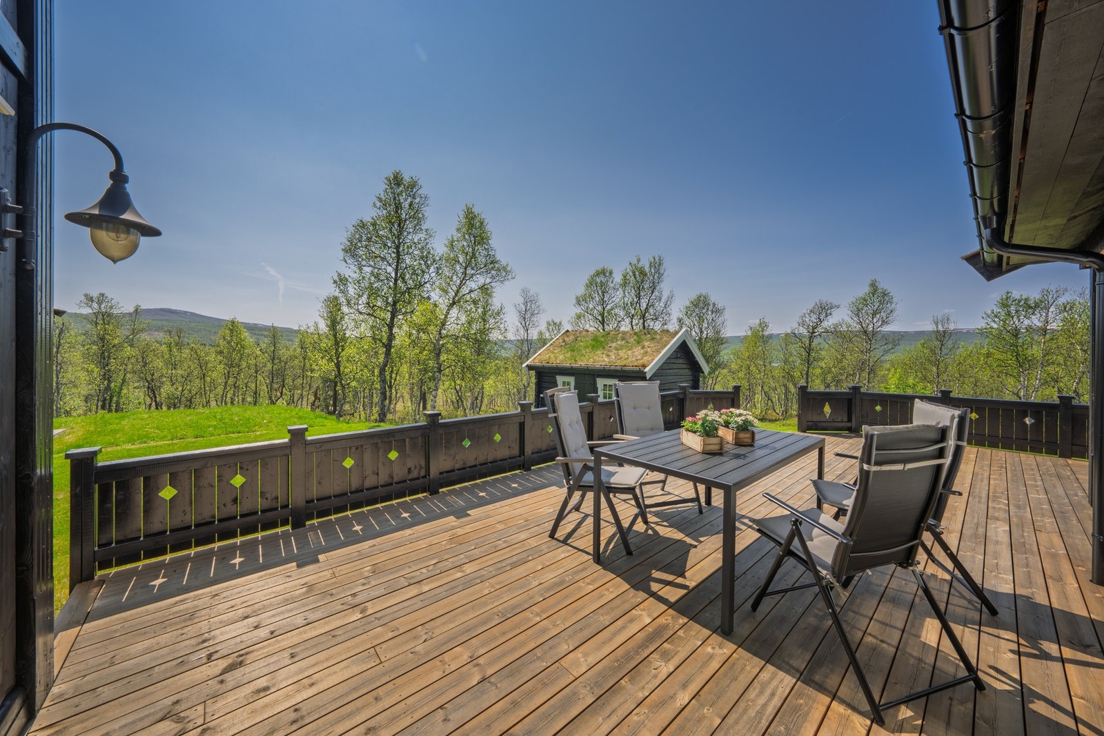 Svær terrasse som strekker seg rundt store deler av hytten. Galleribilde