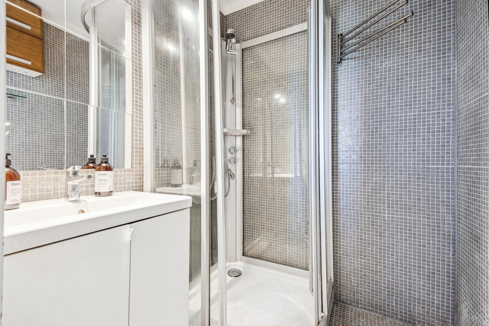 Badet har flislagt, og innredet med vegghengt servantskap og ovenpåliggende servant med armatur. Speil med overlys gir god belysning, og dusjkabinett med dusjarmatur er praktisk plassert. Galleribilde