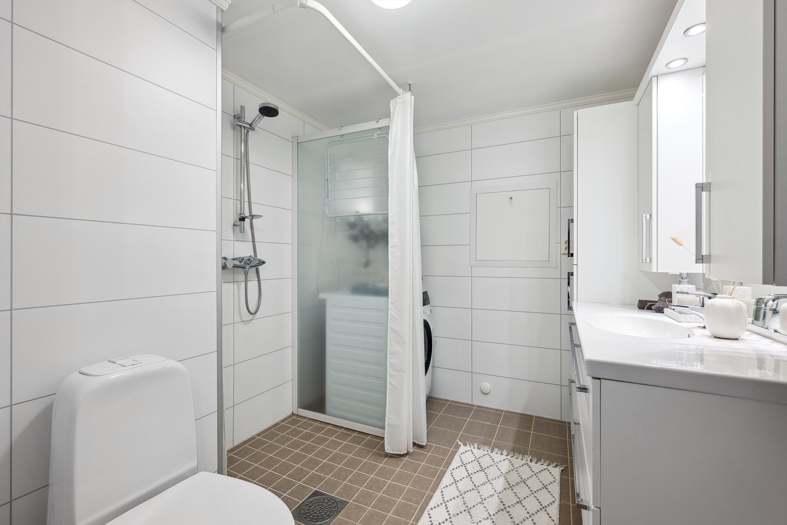 Bad med stor baderomsinnredning, wc, dusj og opplegg for vaskemaskin. Galleribilde